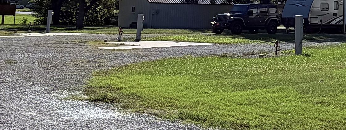 Concrete pad at an RV site beside the gravel drive