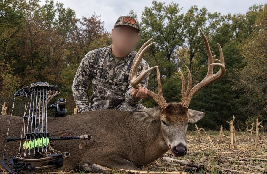 Hunter with a large whitetail buck taken with a bow