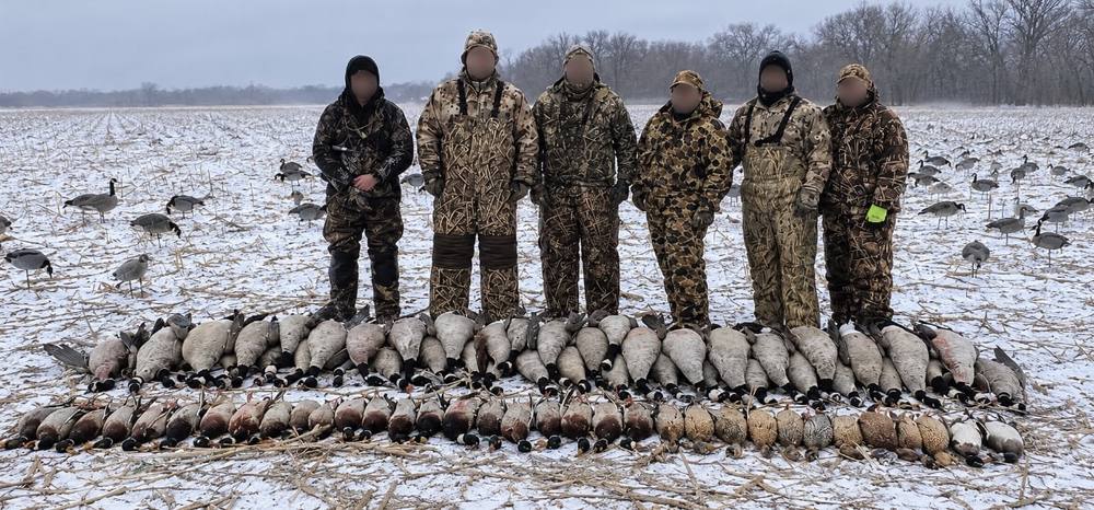 Group of waterfowl hunters with a field full of geese and ducks